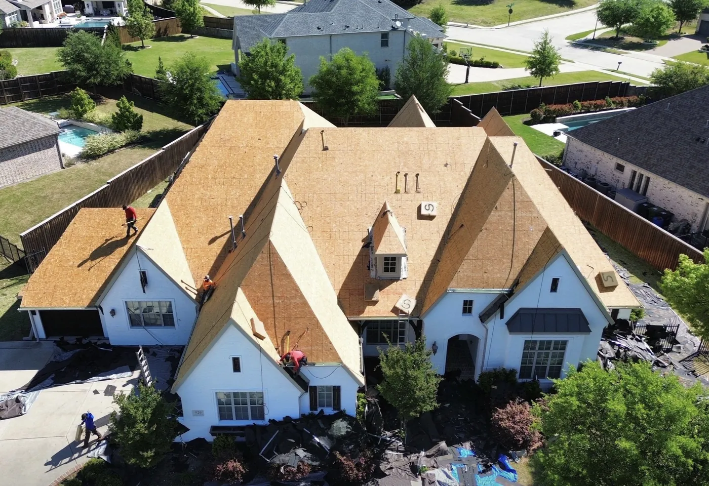Aerial view of a TopLine Roofing job stripped back to bare decking, the crew working across the exposed sheets